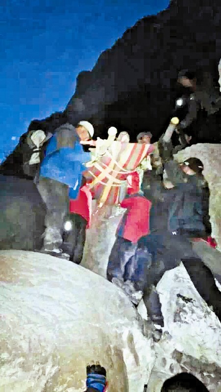 救援隊(duì)員用自制的簡易擔(dān)架抬傷者。